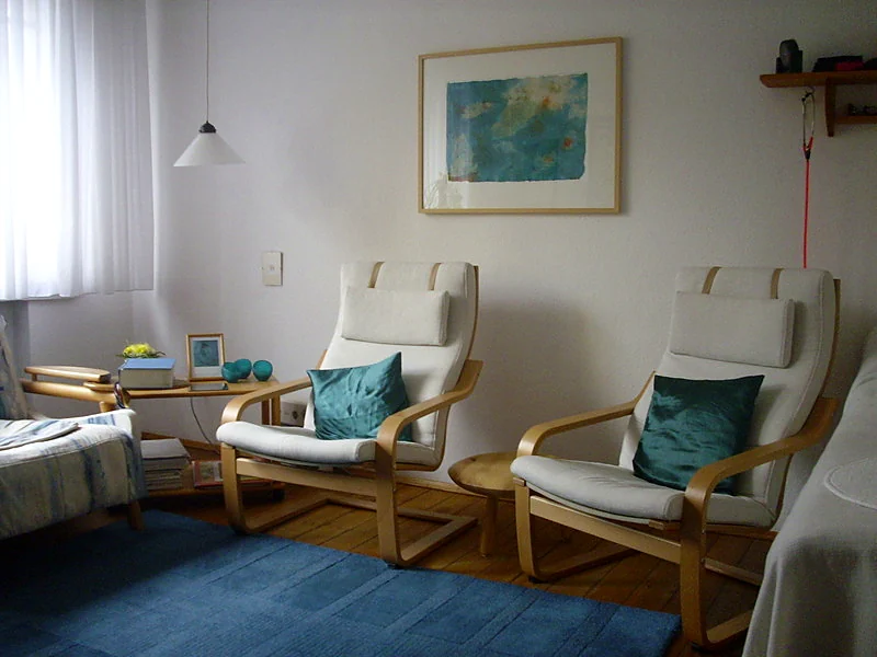 Behandlungszimmer der Praxis mit zwei Sesseln, Bild an der Wand und blauem Teppich